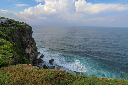 印度尼西亚巴厘岛的乌鲁瓦图悬崖与凉亭和蓝色大海的景色 寺的美丽风景 白天有五颜六色的鲜花前景 高悬崖风景秀丽的沿海景观爬坡太阳海图片