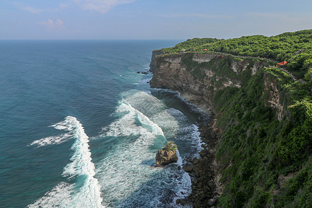 印度尼西亚巴厘岛的乌鲁瓦图悬崖与凉亭和蓝色大海的景色 寺的美丽风景 白天有五颜六色的鲜花前景 高悬崖风景秀丽的沿海景观太阳地平线图片