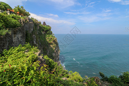 印度尼西亚巴厘岛的乌鲁瓦图悬崖与凉亭和蓝色大海的景色 寺的美丽风景 白天有五颜六色的鲜花前景 高悬崖风景秀丽的沿海景观岩石旅游假图片