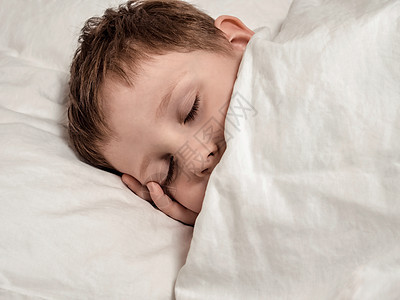 睡在白床上的年轻睡觉男孩图片