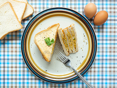 鸡蛋三明治 配料鸡蛋 盐 胡椒和面包放在白盘上 用叉子吃 蓝色背景 用作墙纸早餐食物午餐小吃盘子黄油蒸汽肉汤美食饮食图片