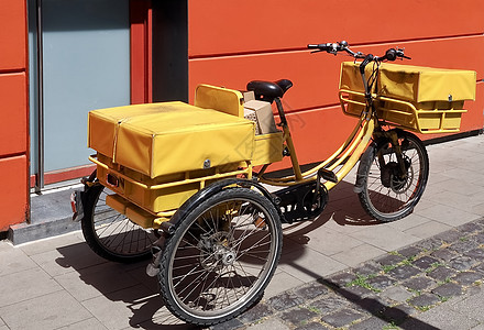 男邮务员或女邮务员执行信件和包裹的黄色自行车图片