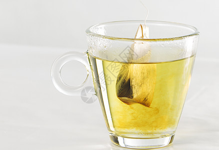 一个茶袋的特写 在玻璃杯 满满水的水与美丽的图片