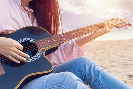 女人的手弹着音响吉他 在日落时在沙滩上用手指捕捉和弦女性音乐音乐会娱乐细绳乐器词曲吉他手音乐家艺术家图片