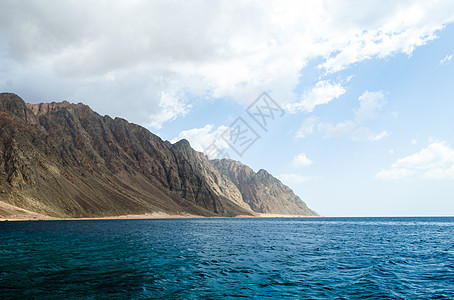 蓝海和高岩山 与天空和乌云相对波浪山脉旅行石头海景海洋旅游海岸蓝色岩石图片