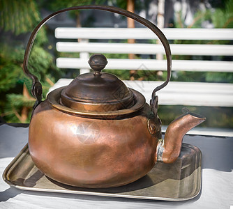 古董铜茶壶和盘子放在桌上图片