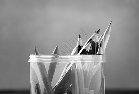 彩色铅笔的特写是放在一个塑料圆盒里 放在靠窗的木桌上 黑白风格基调图片