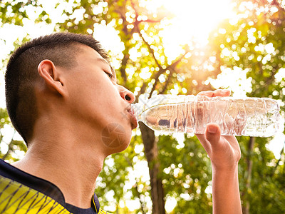 跑步运动员亚洲少年男孩在公园慢跑后喝着瓶装水 喝着酒训练跑步衣服活力运动闲暇生活活动口渴男生背景