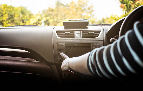 在阳光明媚的日子 年轻女性驾驶汽车 在汽车中按下收音机按钮图片