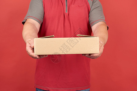 穿红色T恤衫的成年男子 拿着红衣纸板棕色盒子包装命令男性纸盒运输船运工人销售货物男人图片