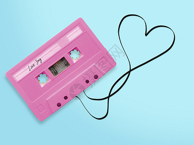 粉红色录音带带 上面贴有标签的爱情歌曲夹在胶带丝带上 心脏形状与蓝色背景隔绝 最高视图图片