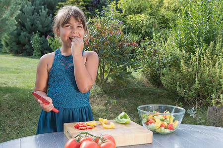 微笑的小女孩正在品尝新鲜沙拉蔬菜图片