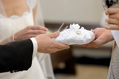 新娘和新郎握着结婚戒指的手夫妻仪式婚姻婚礼庆典枕头蕾丝订婚玫瑰珠宝图片