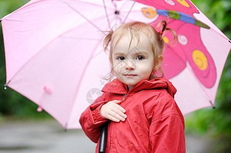 秋天下雨时的可爱小孩女孩雨滴人行道红色靴子水坑季节微笑孩子乐趣农村图片