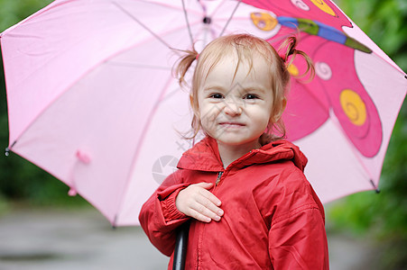 秋天下雨时的可爱小孩女孩童年人行道孩子微笑靴子红色雨滴乐趣水坑雨衣图片