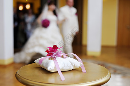 枕头上两个结婚戒指订婚首饰丝带婚礼夫妻宗教紫色婚姻珠宝粉色图片