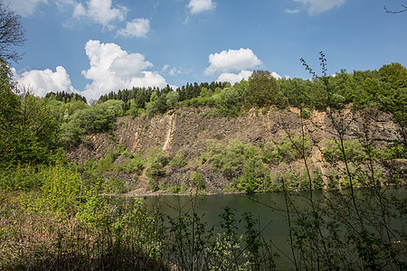 山坡由湖边的拜萨尔特岩石制成火山岩植物天空喷发绿色树木矿物质棕色树叶蓝色图片