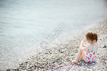 在石滩海滩上可爱的小孩女孩图片