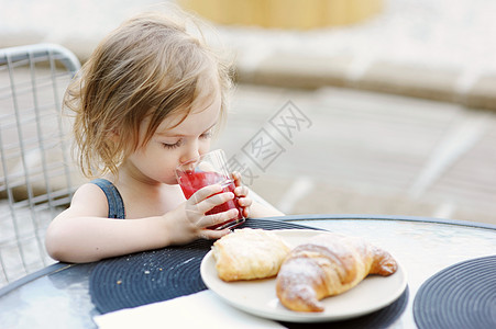 微笑的小女孩吃早饭家庭生活孩子快乐羊角果汁女孩女性桌子乐趣图片