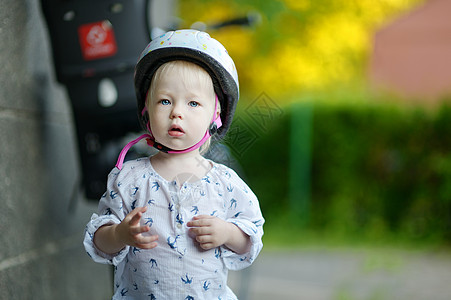 小女孩准备骑单车了孩子婴儿公园阳光乐趣座位女孩车辆活动头盔图片