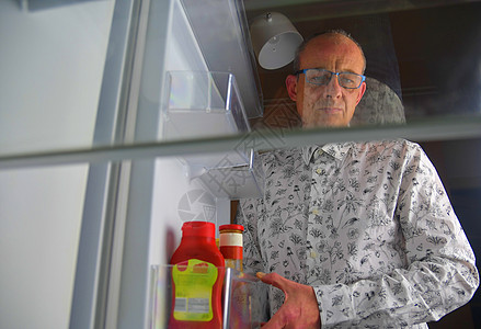 一个饥饿的人在冰箱里寻找食物的画像 饮食概念 — 困惑的中年男子在厨房的空冰箱里寻找食物图片