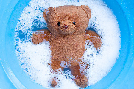 洗衣洗涤水溶解之前 在洗衣中用肥皂灰熊垫圈织物身体泡沫浴缸粉末洗涤剂工作机器衣夹图片