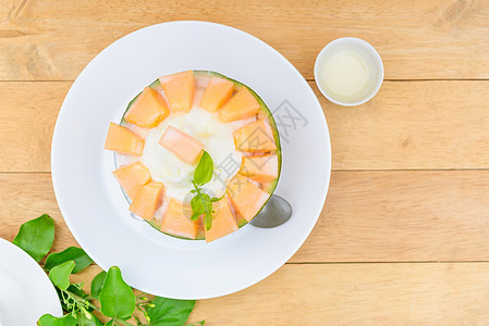 木桌上有甜甜冷凝固牛奶的环冰桌子香草甜点派对食物冰淇淋甜瓜美食杏仁浇头图片