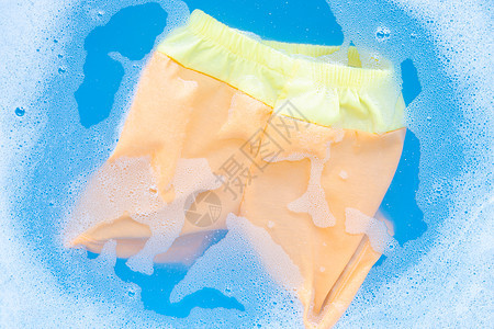 黄色和橙色婴儿短裤浸泡在婴儿洗衣洗涤剂瓦特中袜子连体衣家庭衬衫衣夹玩具女孩孩子绳索篮子图片