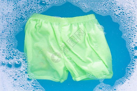 绿色的婴儿短裤浸泡在婴儿洗衣中 清洁剂水脱落孩子生活新生洗衣店玩具男生蓝色家庭纺织品卫生图片