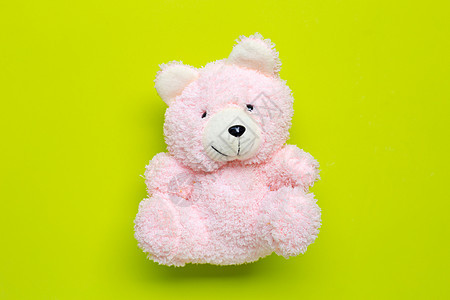 玩具粉色熊在绿色背景图片