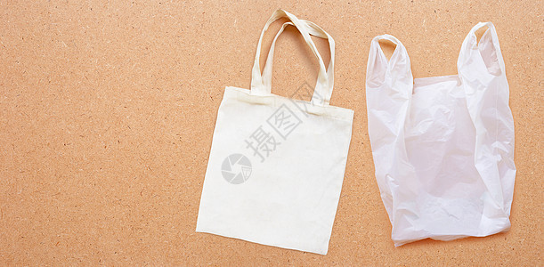 胶合板背景上带白色塑料袋的白色织物袋回收帆布市场零售手提包运动织物小路细绳背包图片