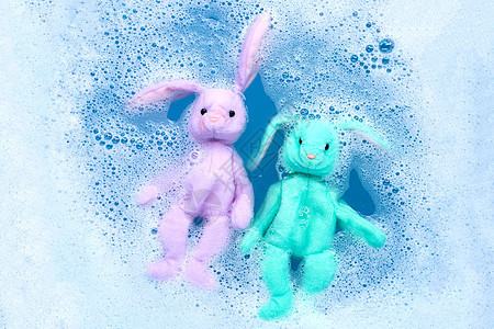 洗衣洗涤水中浸泡的兔子娃娃 在溶解之前家务衣夹蓝色身体洗衣店洗澡浴缸垫圈衣服搪瓷图片