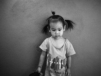 亚洲小女孩独自站在房间里 身处灰色背景图片