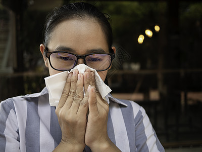 亚裔年轻女子用握住的组织和吹鼻孔打眼镜 流鼻涕 流感季节 健康和医疗概念药品温度过敏症状眼镜发烧疾病咳嗽喷嚏女士图片