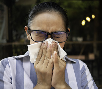 亚裔年轻女子用握住的组织和吹鼻孔打眼镜 流鼻涕 流感季节 健康和医疗概念咳嗽感染女性眼镜温度卫生纸女孩药品过敏疾病图片