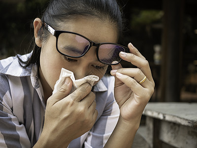 亚裔年轻女子用握住的组织和吹鼻孔打眼镜 流鼻涕 流感季节 健康和医疗概念喷嚏温度过敏女孩药品发烧鼻子感染症状女性图片