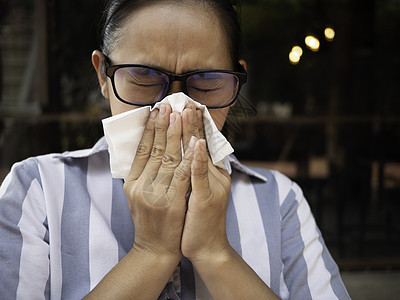 亚裔年轻女子用握住的组织和吹鼻孔打眼镜 流鼻涕 流感季节 健康和医疗概念卫生纸药品喷嚏女性发烧女士鼻子感染疾病温度图片