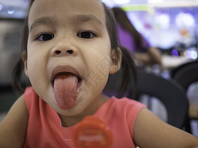 亚裔小孩在商场食品法庭吃下多彩糖果后 便用舌头露出她的舌头图片