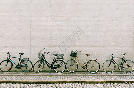 四辆自行车站在一堵白砖墙附近 几辆不同的自行车停在哥本哈根的一条空街上图片