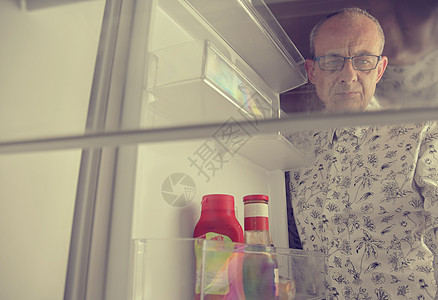 一位饥饿的老人在冰箱里寻找食物的画像 饮食概念 — 困惑的成年男子在厨房的空冰箱里寻找食物图片