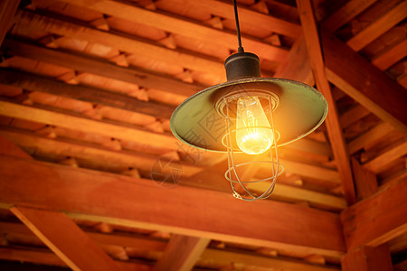 白炽灯泡悬挂在亚洲乡村屋顶屋山墙角的天花板上 白炽灯泡大胆的风格和低技术含量 爱迪生灯图片
