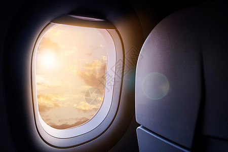 从飞机窗户看到的云彩和天空 金色的阳光和镜头光晕图片
