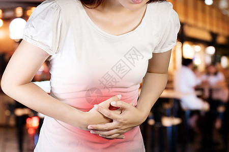 女人患有胃痛或胃肠病 医疗保健和医学的概念 疼痛呈红色 在模糊餐厅背景上使用剪切路径进行隔离图片