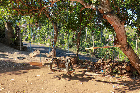 挂在热带树上的儿童秋千 巴厘岛孩子的廉价乐趣 由绳索 旧轮胎 树枝 木棍和木板制成的秋千 热带植被和蔚蓝的天空活动孩子们公园游戏图片