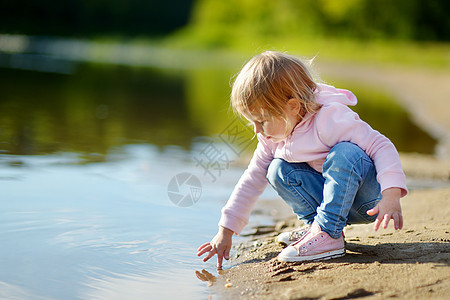 可爱的幼儿女孩在河边玩耍图片