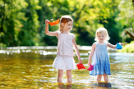 两个小妹妹玩纸船的两姐妹溪流姐姐享受折纸孩子们女性家庭幸福快乐自由图片