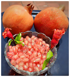 两颗石榴和石榴籽放在碗里 里面有闪亮的红色珠宝 花蕾放在碗里 漂亮地放在黑盘里木头义者甜点健康作品营养热带饮食浆果水果图片