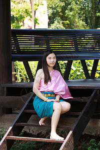 在河边古屋的海滨亭前 身着泰国传统服装 面带微笑的泰国亚裔礼貌女性 20 多岁的美丽亚洲女模特图片