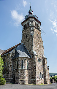 的古老基督教教堂钟楼历史绿色棕色石工蓝色灌木丛天空窗户灌木图片