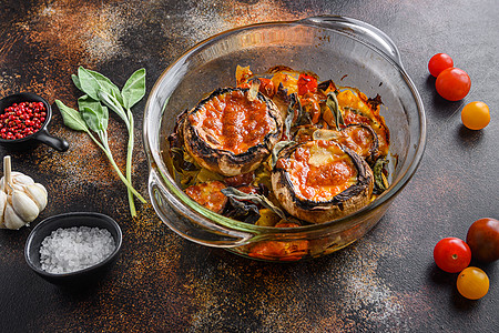 海鲜香菇粥波多贝罗蘑菇 以切达奶酪 樱桃西红柿和芝士在玻璃锅中烤制成的香草 在古老的黑底深色面观下背景